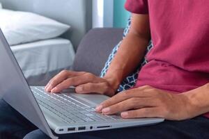Man working on laptop in his bedroom. Working from home, working on holiday or working from anywhere concept. photo