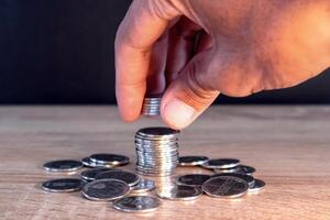Man hand putting coins on stack on wooden table photo