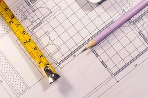 Top view of building layout with pencil and roll up metal tape measure photo
