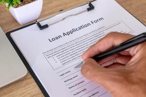 Close up view of hand holding pen to fill out loan application form photo