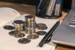 Stack of coins on a book on a wooden work table photo