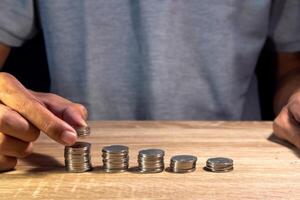 Man makes stacks of coins on wooden table to calculate cost or budget photo