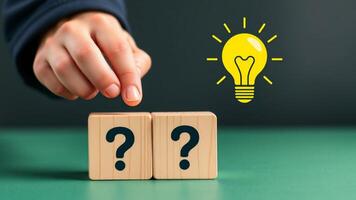 Creative idea and innovation concept. Hand picking wooden cube block with question mark and light bulb icon photo