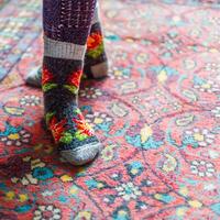 legs in warm woven wool socks standing on red ornate carpet floor at home photo