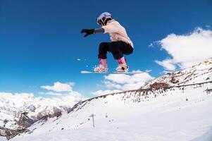 Portrait of a snowboarder doing an extreme trick. Grabbing the front edge of a snowboard with your hand while jumping from a kicker photo