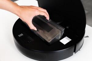 container with dust from a robot vacuum cleaner in hands against the background of a vacuum cleaner photo