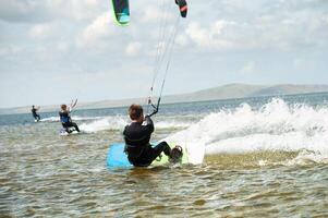 Kitesurfing, kiteboarding, action photo. Man from behind actively and quickly rides on water on kiteboard, sailing, adrenaline photo