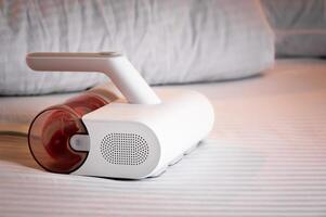 Specialized vacuum cleaner for removing linen mites and disinfecting bed linen and bedding. Vacuum cleaner with UV lamp on the bed photo