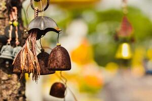 Rustic Wind Chimes Hanging from Tree, Close-Up of Weathered Bells with Vibrant Background, Stock Image for Meditation, Serenity Concepts, Spiritual Photography, and Peaceful Outdoor Settings. photo