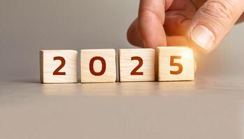 Hand Turning Wooden Cubes from 2024 to 2025, New Year Concept with Glowing Light, Stock Image for Business, Year-End Reviews, Future Planning, and Inspirational Content for Blogs or Websites. photo