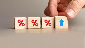 Hand Adjusting Wooden Blocks with Red Percentage Symbols and Upward Arrow Icon, Stock Image for Financial Concepts, Interest Rate Hikes, Business Growth, Economics, and Investment Trends. photo