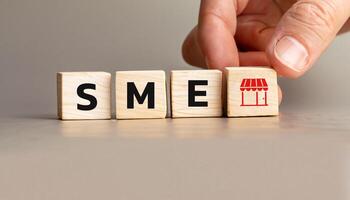 SME Concept with Wooden Cubes Representing Small and Medium Enterprises, Hand Arranging Blocks with Shop Icon, Symbolizing Retail and Local Business Development. photo