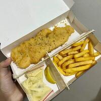 Savoring every crispy bite of this classic dish. The perfect blend of flaky fish and golden fries, it is a culinary hug in every mouthful photo