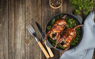 Baked quail with herbs on a wooden table. Side view. Banner. Copy space. photo