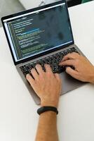 Programmer, typing with two hands, one of which is wearing a watch. photo