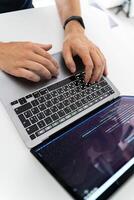 Programmer typing on a laptop, side view photo