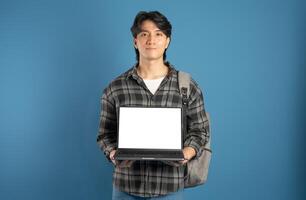 Portrait of Asian male student posing on blue background photo