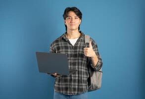 Portrait of Asian male student posing on blue background photo