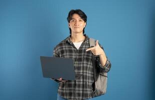 Portrait of Asian male student posing on blue background photo