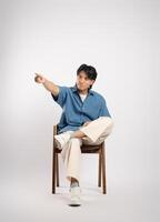 Portrait of young Asian business man sitting in chair, isolated on white background photo