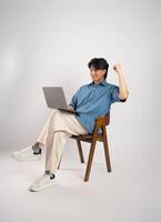 Portrait of young Asian business man sitting in chair, isolated on white background photo