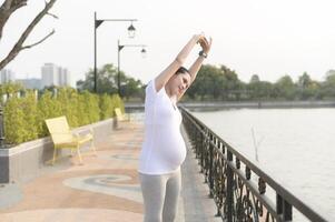Beautiful pregnant woman stretching and exercising in the park photo