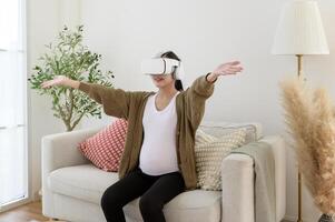 Pregnant woman wearing vr box using future technology for entertainment in living room photo