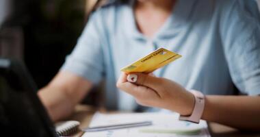 Relaxed female freelancer sitting at desk shopping online using a credit card and paying via digital tablet in home office. Work from home photo
