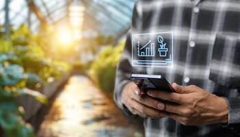 Man holding smartphone in greenhouse with graph on screen photo
