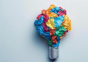 Lightbulb filled with colorful, crumpled paper, symbolizing creativity and brainstorming. The vibrant colors of the paper represent diverse ideas and innovative thinking photo