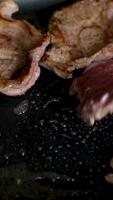 Schritt durch Schritt, ein Mann schneidet Fleisch in Steaks und Fritten Sie im ein braten schwenken roh Rippe Auge Steaks mit Gewürze und Kräuter auf ein hölzern Küche Tisch, streuen mit Meer Salz- und Pfeffer auf oben. video