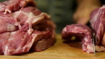 Step by step, a man cuts meat into steaks and fries them in a frying pan raw rib eye steaks with spices and herbs on a wooden kitchen table, sprinkle with sea salt and peppers on top. video