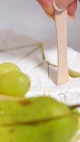 cheese with white mold Brie and grapes served with honey in a restaurant On a square plate with wooden skewers tasty delicacy expensive video