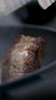 fry meat in a frying pan Adding smashed garlic and thyme to beefsteak into frying pan video