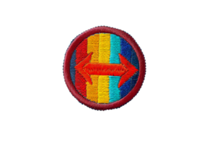 A circular embroidered patch with bold colors and red arrows pointing both directions on a blue and orange striped background. png