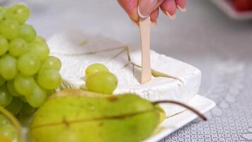 cheese with white mold Brie and grapes served with honey in a restaurant On a square plate with wooden skewers tasty delicacy expensive video