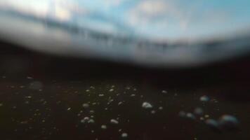 Over and Under River Surface with Water Reflections - Low Angle View. Underwater Split View with Waves at Sunny Summer Day - Super Slow Motion video