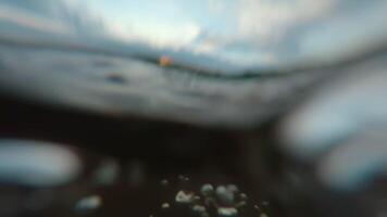 Over and Under River Surface with Water Reflections - Low Angle View. Underwater Split View with Waves at Sunny Summer Day - Super Slow Motion video