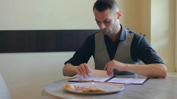 Handsome Young Man is Writing a Document in Pizzeria Cafe. Office Employee Has a Break. Middle Close-Up View, Dynamic Shot video