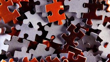 Background of Colored Puzzle Pieces that Slowly Rotating Counterclockwise - Top View, Close-Up. Texture of Incomplete Red and Grey Jigsaw Puzzle with Low Key Light - Left Rotation video