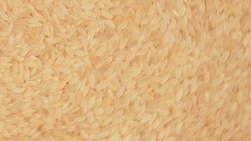 Dry Uncooked Parboiled Rice Background Rotating Counter-Clockwise - Top View. Scattered Raw Long Grain Rice. Asian Cuisine and Culture. Healthy Eating Ingredients. Diet Food. Angular Rotation Left video