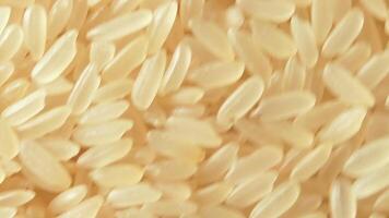 Dry Uncooked Parboiled Rice Background Rotating Counter-Clockwise - Top View. Scattered Raw Long Grain Rice. Asian Cuisine and Culture. Healthy Eating Ingredients. Diet Food. Angular Rotation Left video