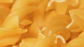 Uncooked Fusilli Pasta Rotating - Macro. Fat and Unhealthy Food. Dry Spiral Macaroni - Close-Up. Italian Culture and Cuisine. Raw Golden Pasta video