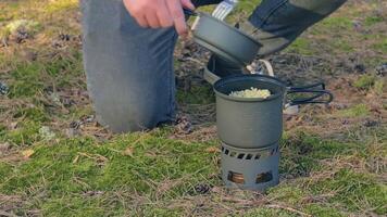 Man in a Forest is Cooking Pasta With Canned Stew Using a Small Cook Set. Tourist in a Hike is Preparing for the Lunch. Close-Up View, Static Shot video