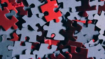 Background of Colored Puzzle Pieces that Slowly Rotating Clockwise - Top View, Close-Up. Texture of Incomplete Red and Grey Jigsaw Puzzle with Low Key Light - Right Rotation video