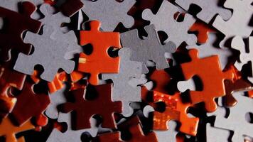 Background of Colored Puzzle Pieces that Slowly Rotating Counterclockwise - Top View, Close-Up. Texture of Incomplete Red and Grey Jigsaw Puzzle - Left Rotation video