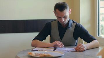 Handsome Young Man is Writing a Document in Pizzeria Cafe. Office Employee Has a Break. Middle Close-Up View, Dynamic Shot video