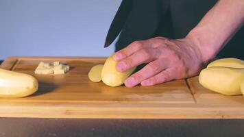 Chef in Black Uniform is Slicing Raw Potato. Man in a Kitchen is Cutting Potato and Preparing Ingredients for Cooking - Slow Motion. Static Shot video
