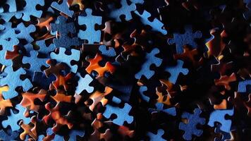Background of Colored Puzzle Pieces that Slowly Rotating Clockwise - Top View. Texture of Incomplete Red and Blue Jigsaw Puzzle with Low Key Light - Right Rotation video
