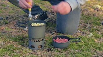 Man in a Forest is Cooking Pasta With Canned Stew Using a Small Cook Set. Tourist in a Hike is Prepearing for the Lunch. Close-Up View, Static Shot video